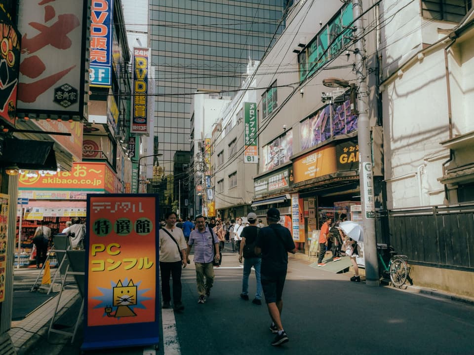 A vibrant street scene in Akihabara, Tokyo, showcasing modern architecture and lively crowd.