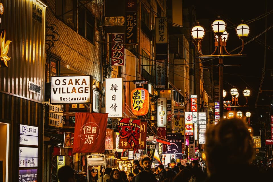 Bustling nightlife in Osaka's Dotonbori, Japan, featuring vibrant signage and a lively street atmosphere.