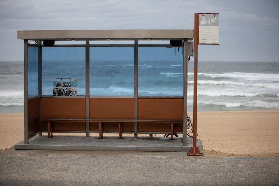 Empty bus stop by a serene beach in Gangneung, South Korea with waves in the background.