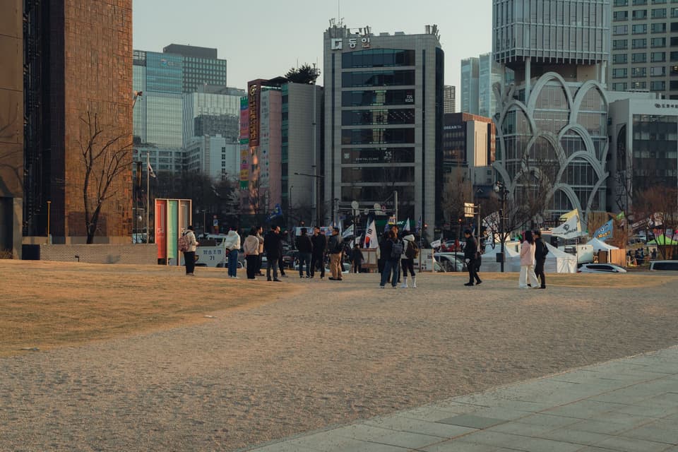 A view of modern architecture and people gathered in a public space in Seoul, South Korea, during daytime.