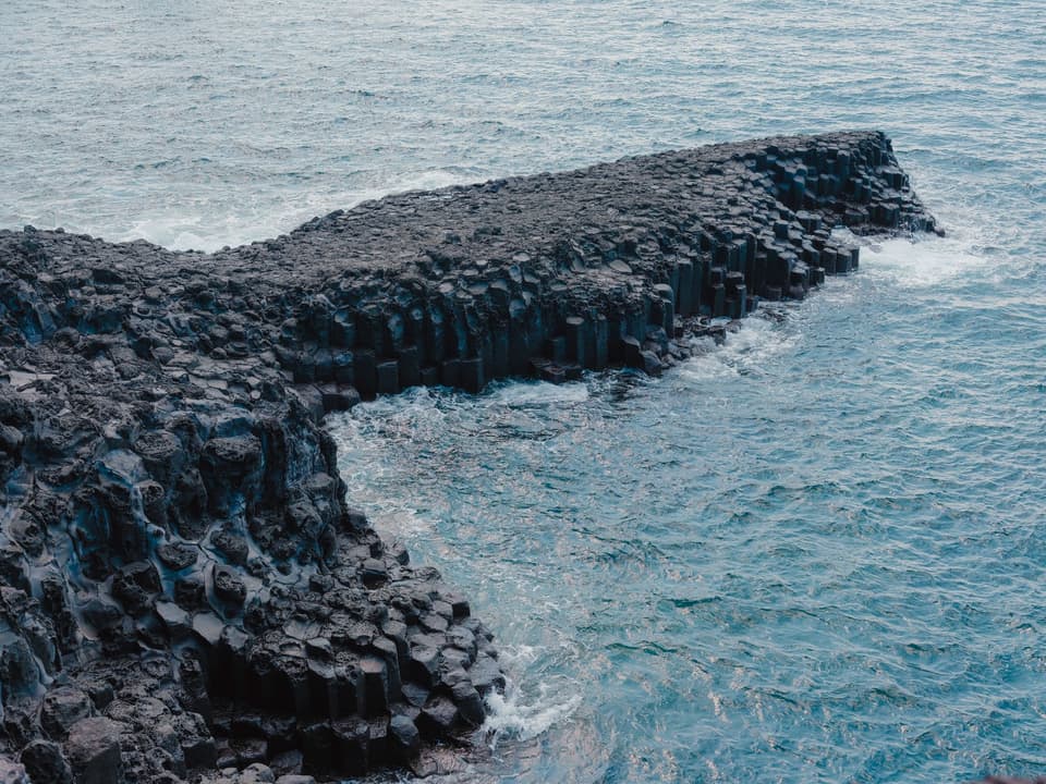Stunning view of basalt columns meeting the ocean at Seogwipo-si, Jeju, Korea.