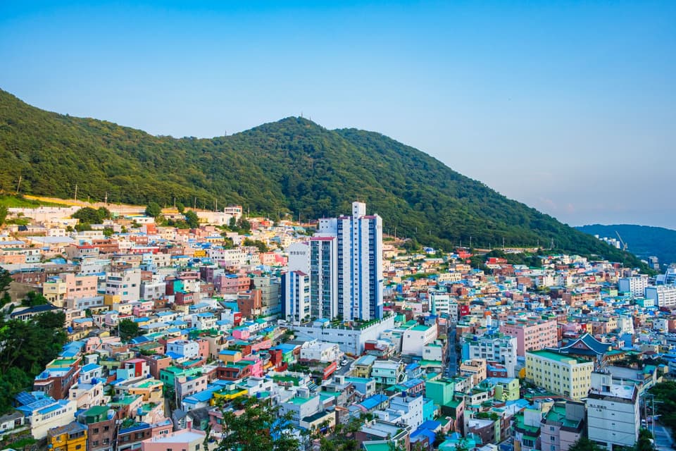 Scenic view of vibrant hillside neighborhoods with mountain backdrop in Busan, South Korea.