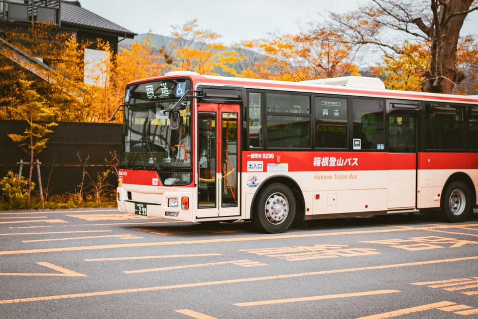 A Hakone Tozan bus captured against vibrant autumn colors in the street.