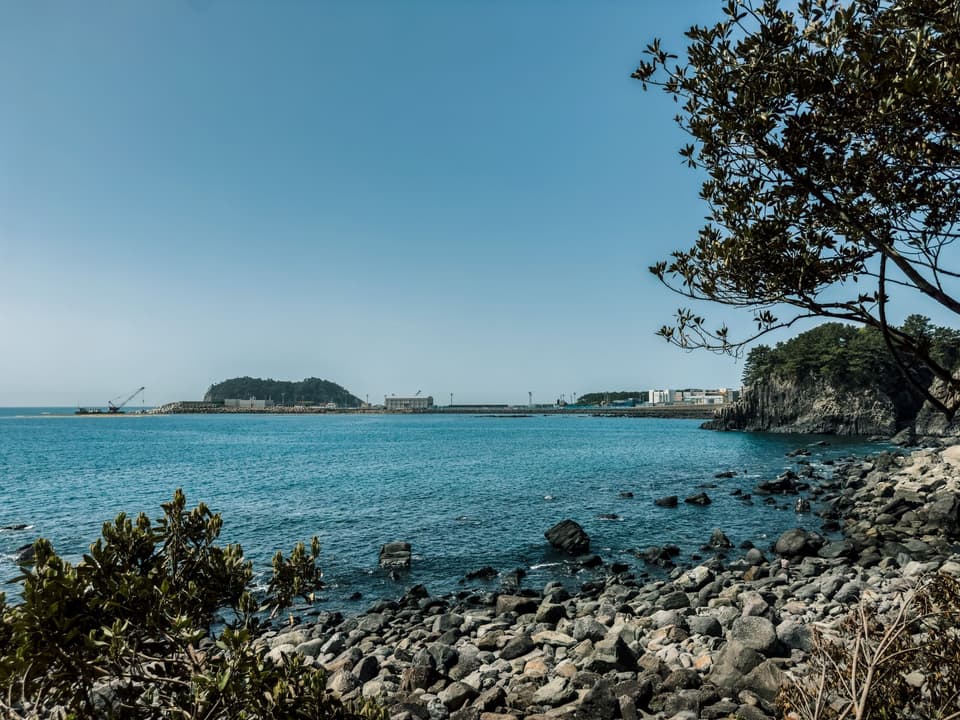Serene coastal landscape of Jeju Island with clear blue sky and tranquil sea, ideal for travel and nature lovers.