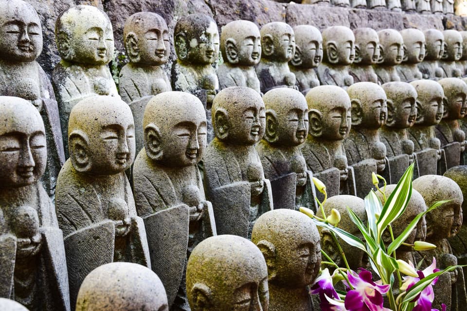 Close-up of numerous small stone Buddha statues at Hase-dera Temple in Kamakura, Japan.