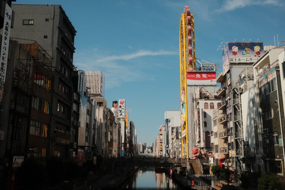 Vibrant Dotonbori canal scene with a prominent Ferris wheel in Osaka, Japan.