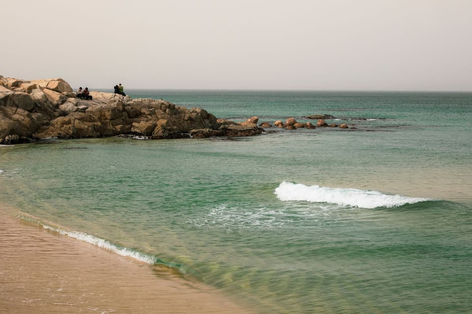 Peaceful beach scene with rocky coast and gentle waves near Sokcho, South Korea.