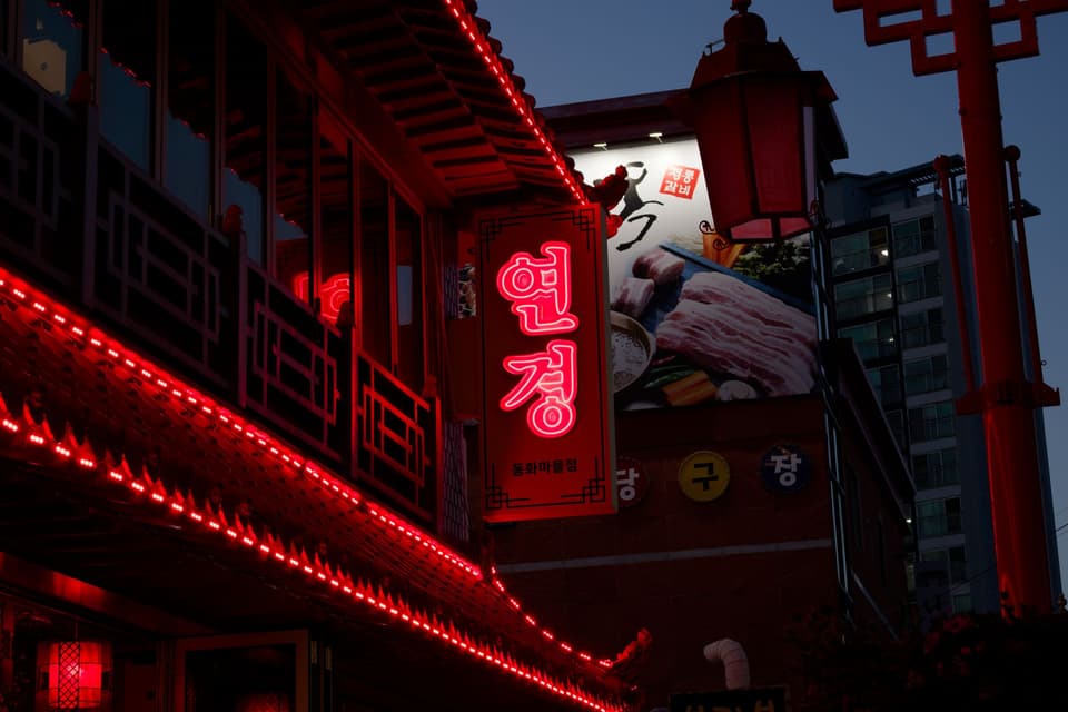 Neon signs illuminating a street in Incheon, South Korea at night, showcasing Korean culture.