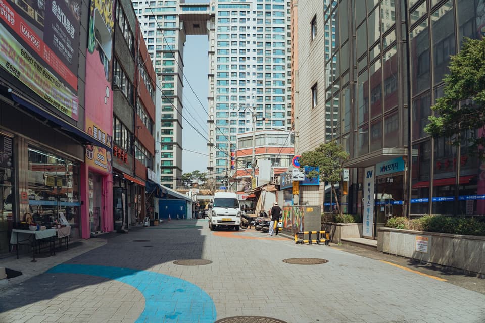 Busy street in Seoul with modern architecture and local shops, captured during the day.