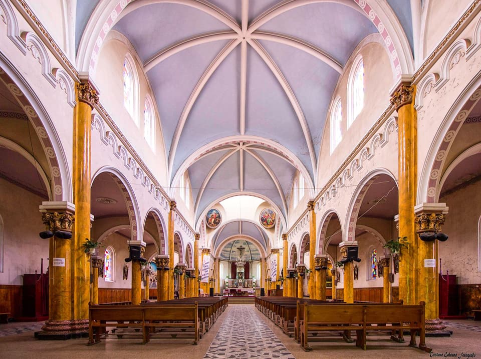 Elegant interior of a Catholic church with vaulted ceilings and ornate design, highlighting religious architecture.