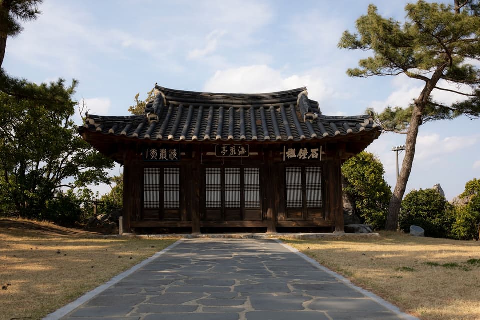 Captivating view of a traditional Korean Hanok surrounded by lush greenery and clear skies.