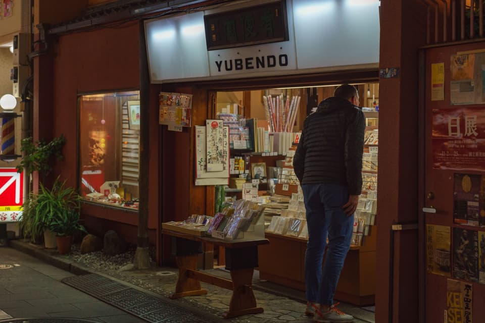 A man browsing books at Yubendo store in Tokyo at night.