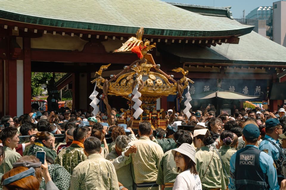 Crowd gathers around a mikoshi during a vibrant festival at a shrine in Tokyo, Japan. Celebrating culture and tradition.