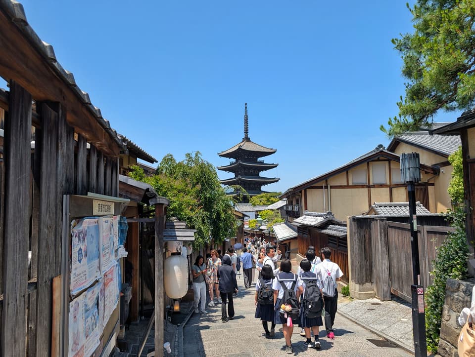 A bustling street scene with tourists near Yasaka Pagoda in Kyoto, Japan on a clear summer day.