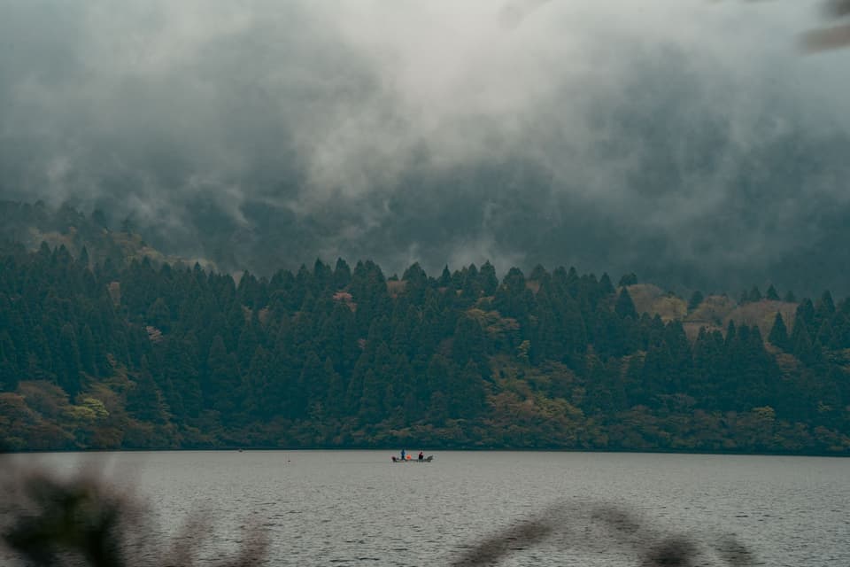 Serene view of Lake Ashi in Hakone, Japan with fog rolling over lush forests.