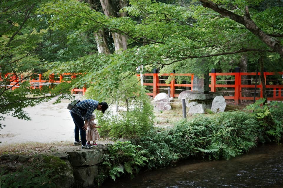 A serene moment between father and child in a Kyoto park by the river.