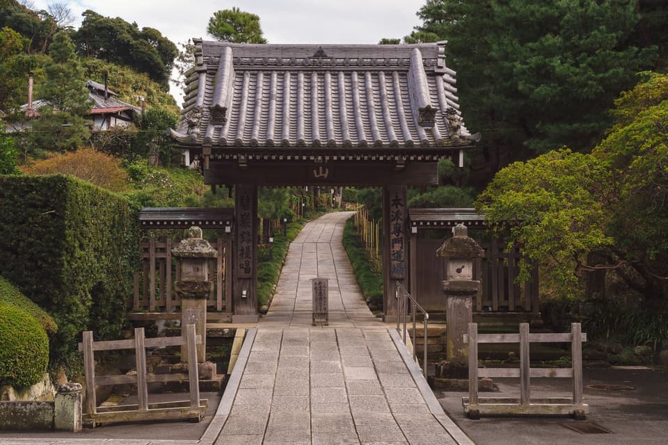 Explore the serene pathway leading to a traditional Japanese gate at Kencho-Ji Temple in Kamakura.