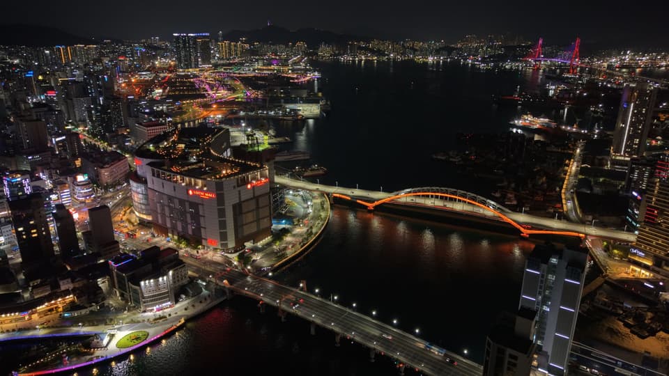A stunning aerial view of Busan, South Korea, showcasing illuminated bridges and cityscape at night.
