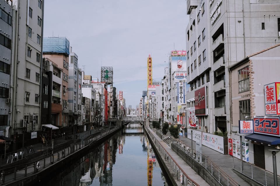 Vibrant urban scene in Osaka, Japan with bustling canal and city buildings.