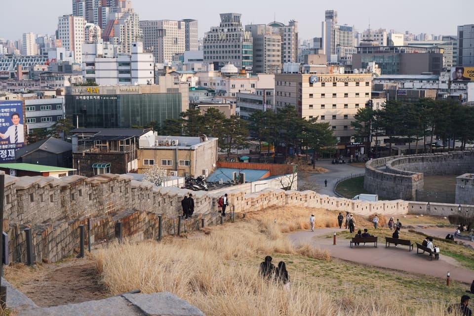 Scenic view of Dongdaemun wall and vibrant Seoul cityscape at sunset.