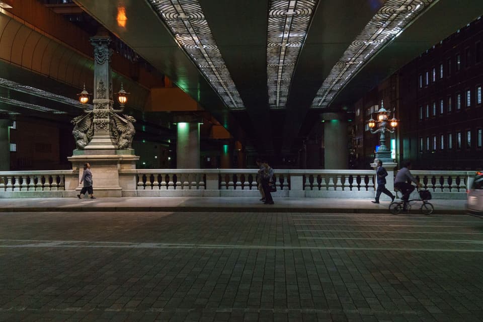 Evening scene on Nihonbashi Bridge in Tokyo with pedestrians and cyclists.