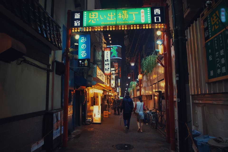 A vibrant scene of people walking in Omoide Yokocho alley in Shinjuku at night.