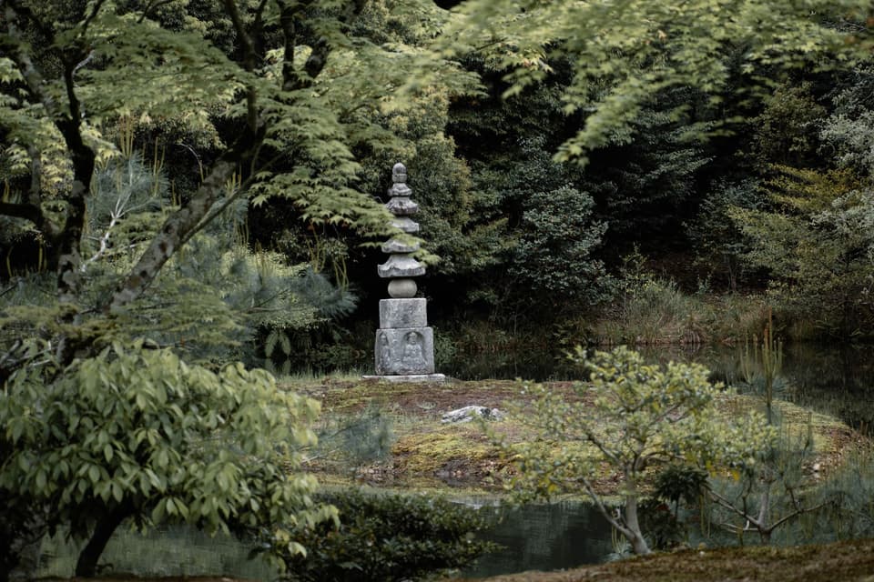Tranquil Japanese garden scene featuring ancient pagoda surrounded by lush greenery in Kyoto, Japan.