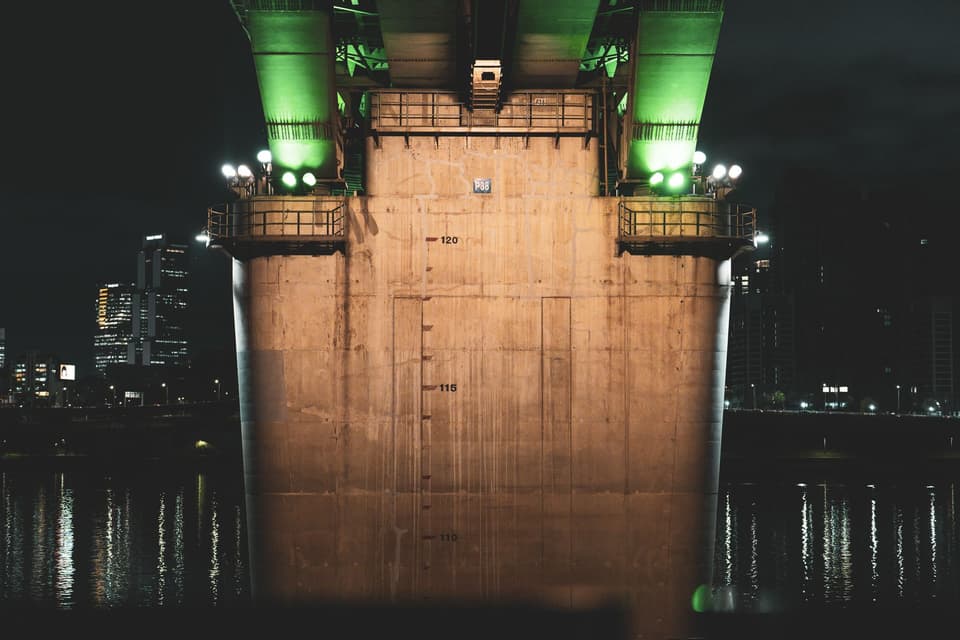 A night view of a brightly lit bridge over the Han River in Seoul, showcasing modern architecture.