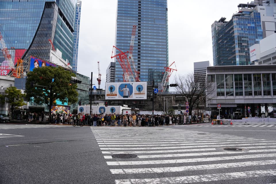 Crowd at a busy Tokyo intersection surrounded by modern skyscrapers and urban architecture.