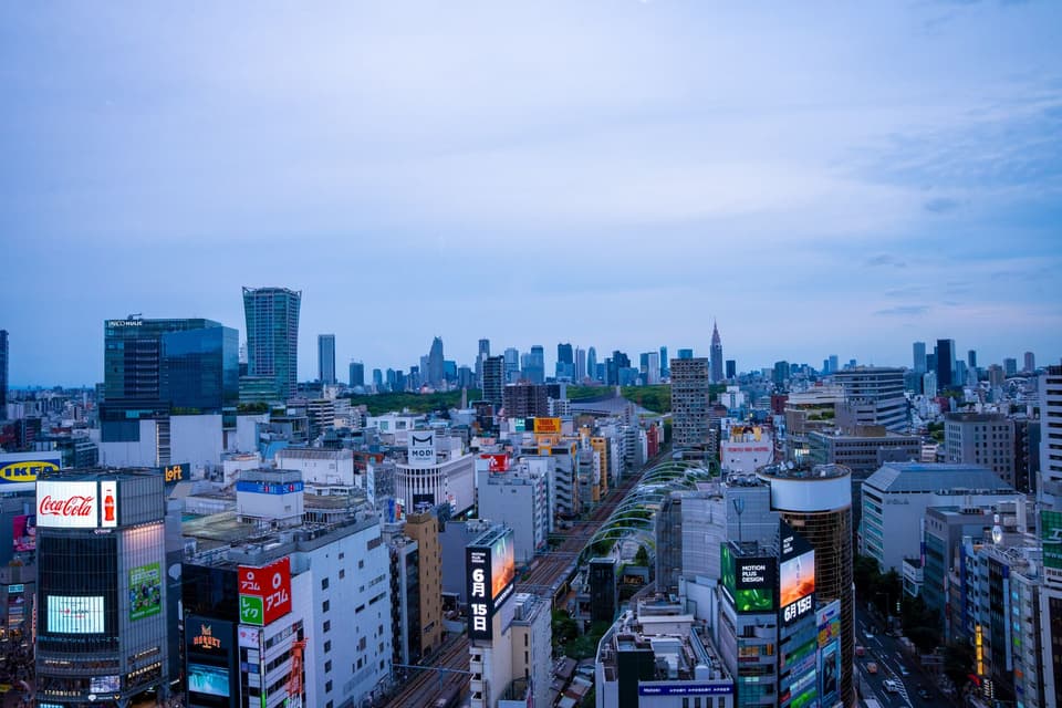 Aerial view of Shibuya skyline with vibrant city lights under a clear evening sky in Tokyo, Japan.