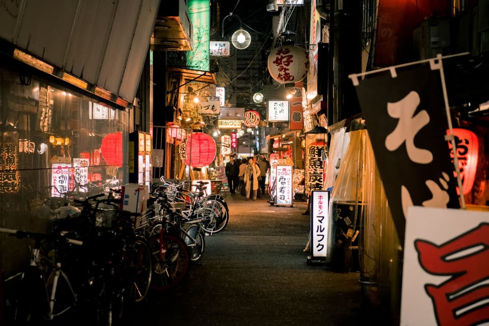 Explore the bustling nightlife in Dotonbori, Osaka with illuminated lanterns, shops, and people.