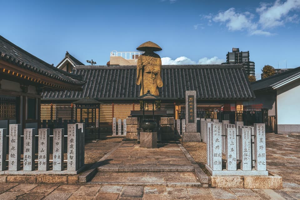 Explore the serene Shitennoji Temple courtyard in Osaka under a clear blue sky.