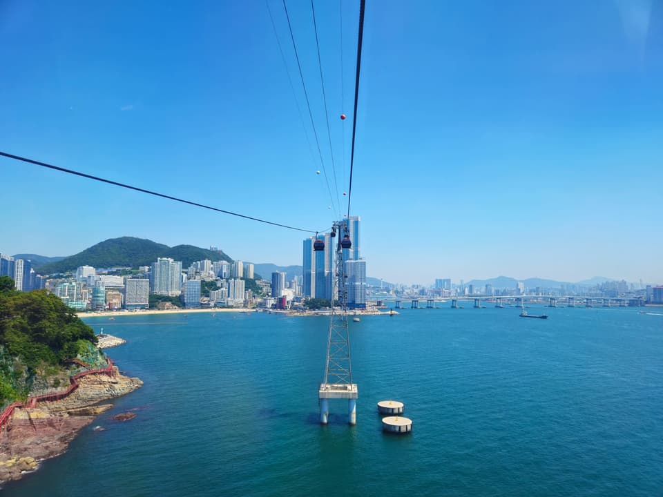 Scenic aerial view of Busan, South Korea with Songdo cable car over the blue sea and city skyline.