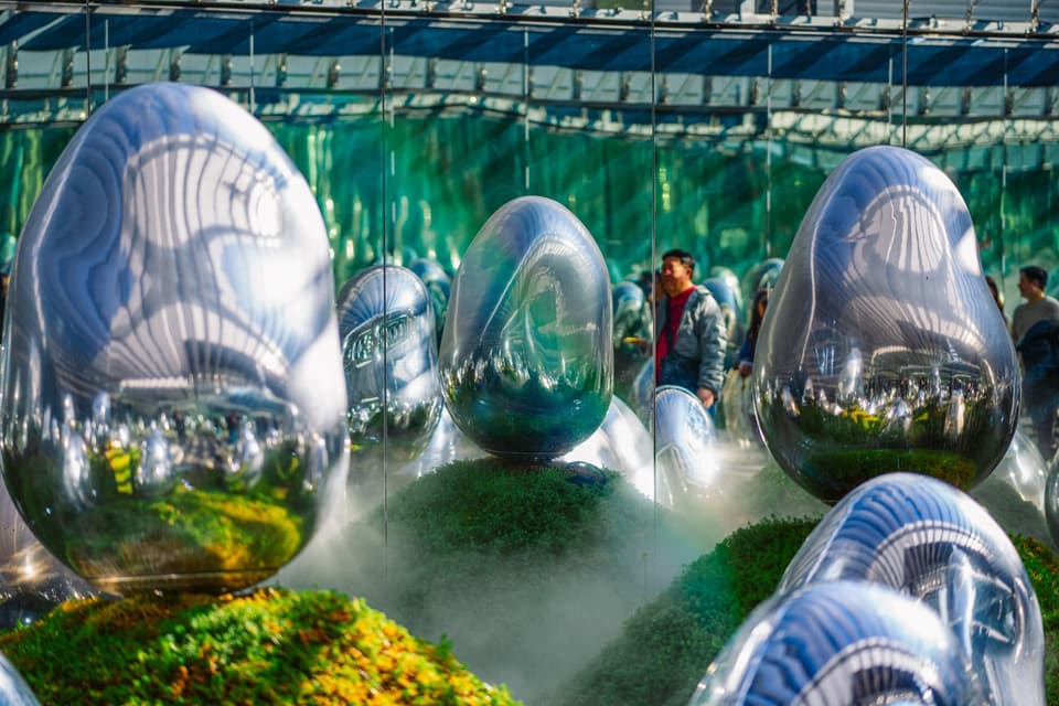 Reflective surreal art installation with mirrored surfaces in Koto City, Tokyo, featuring abstract egg shapes and mist.