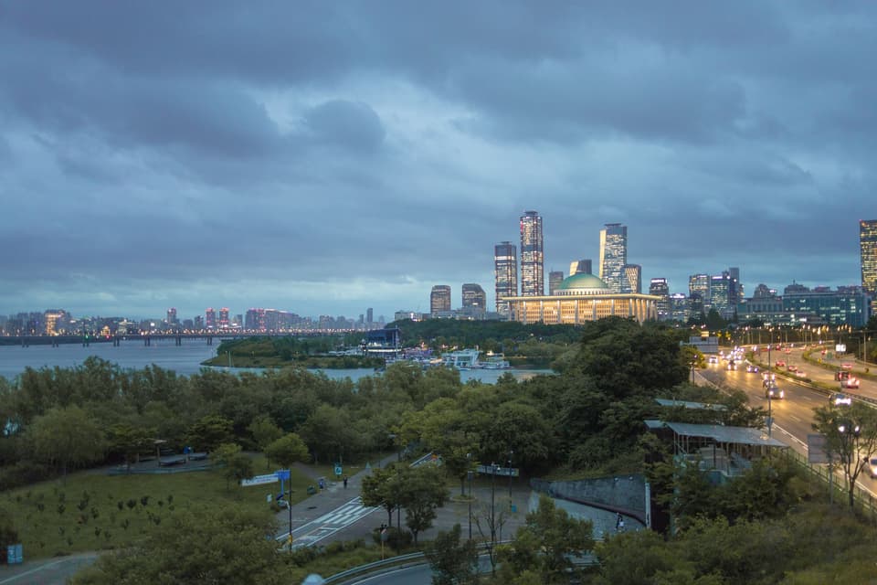 Dynamic view of Seoul's skyline featuring iconic structures and Han River at dusk.