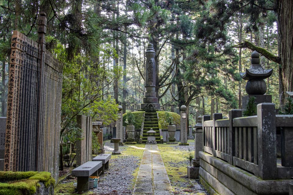 Peaceful view of Okunoin Cemetery in Japan, surrounded by trees and ancient tombs.