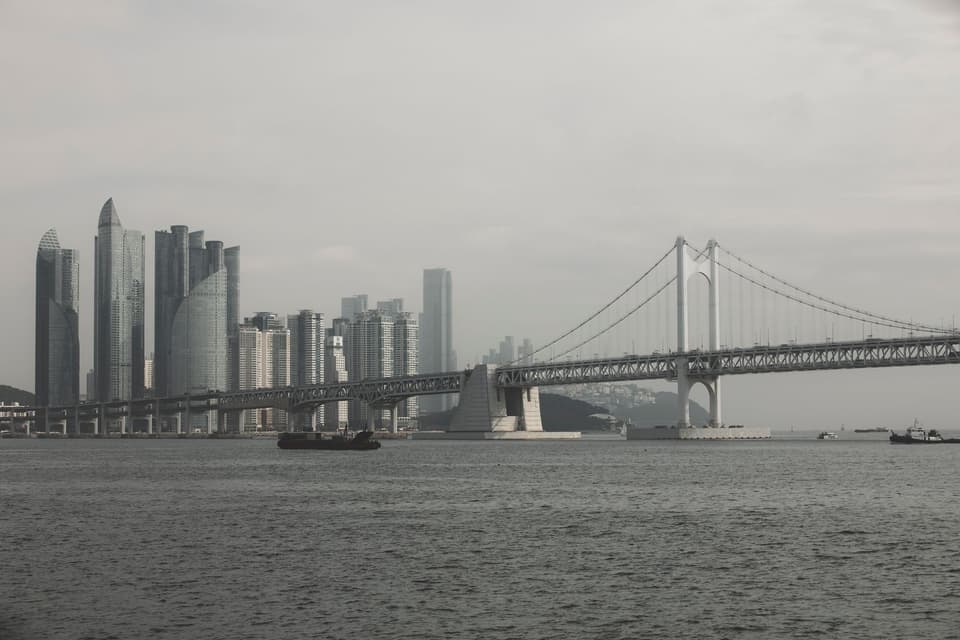 View of Gwangan Bridge and modern skyscrapers in Busan, South Korea, showcasing urban architecture.